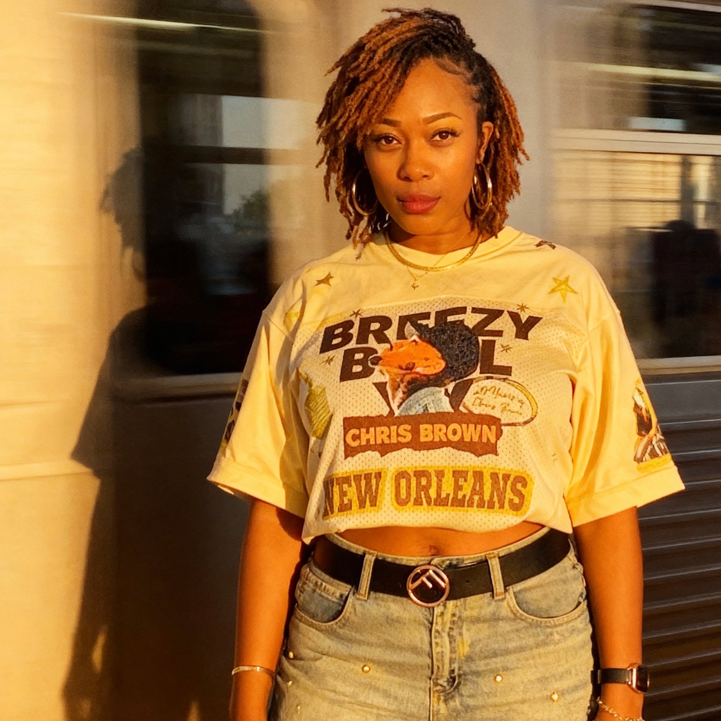 Person wearing a 'Breezy Ball Chris Brown New Orleans' t-shirt and jeans.