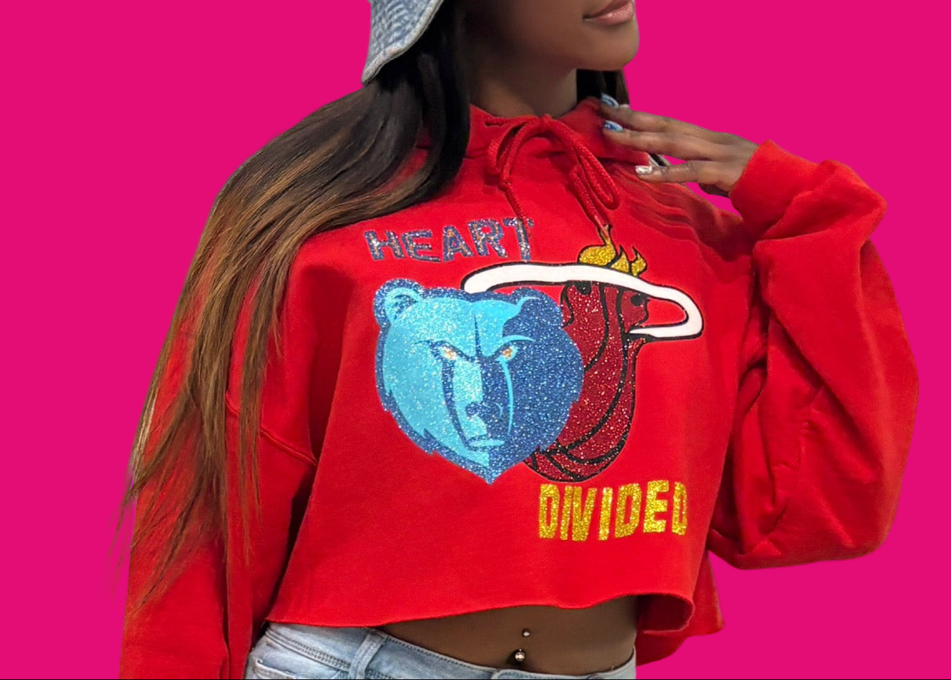 Person wearing a red hoodie with graphic design, light blue jeans, and denim bucket hat against a beige background